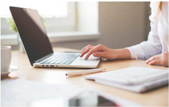 A woman in a white shirt using a white laptop